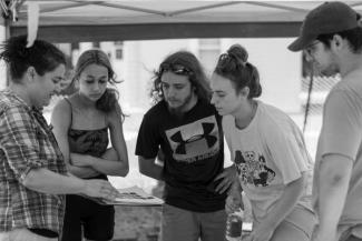Black and white photo of archaeology students collaborating at a field excavation.