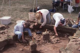 Archaeologists conducting an excavation, carefully uncovering and documenting features at a dig site.