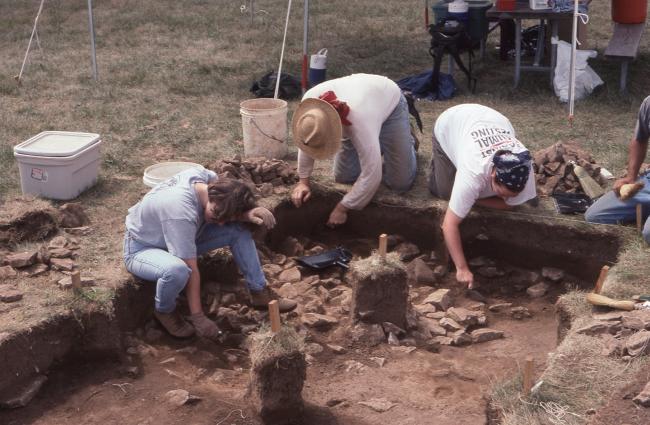 Three student archaeologist excavating an archaeological unit